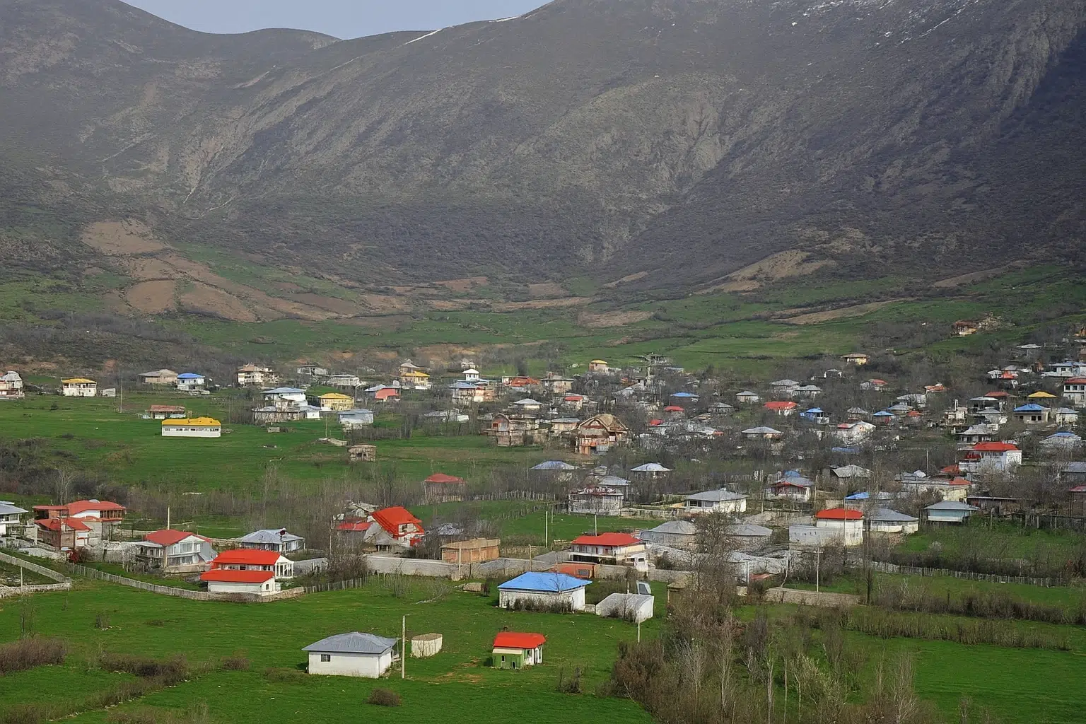 نمای هوایی از خانه‌های روستای داماش در دل کوه‌های البرز با سقف‌های رنگی.