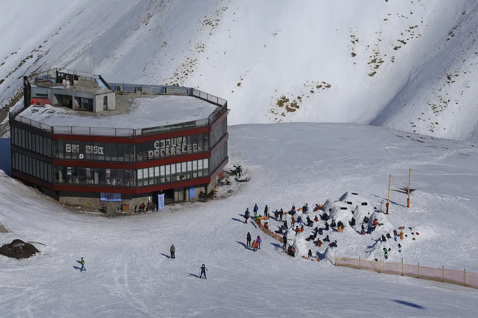 نمای هوایی از پیست دیزین در کرج با اسکی‌بازان و مناظر کوهستانی برفی – پیست اسکی ایران